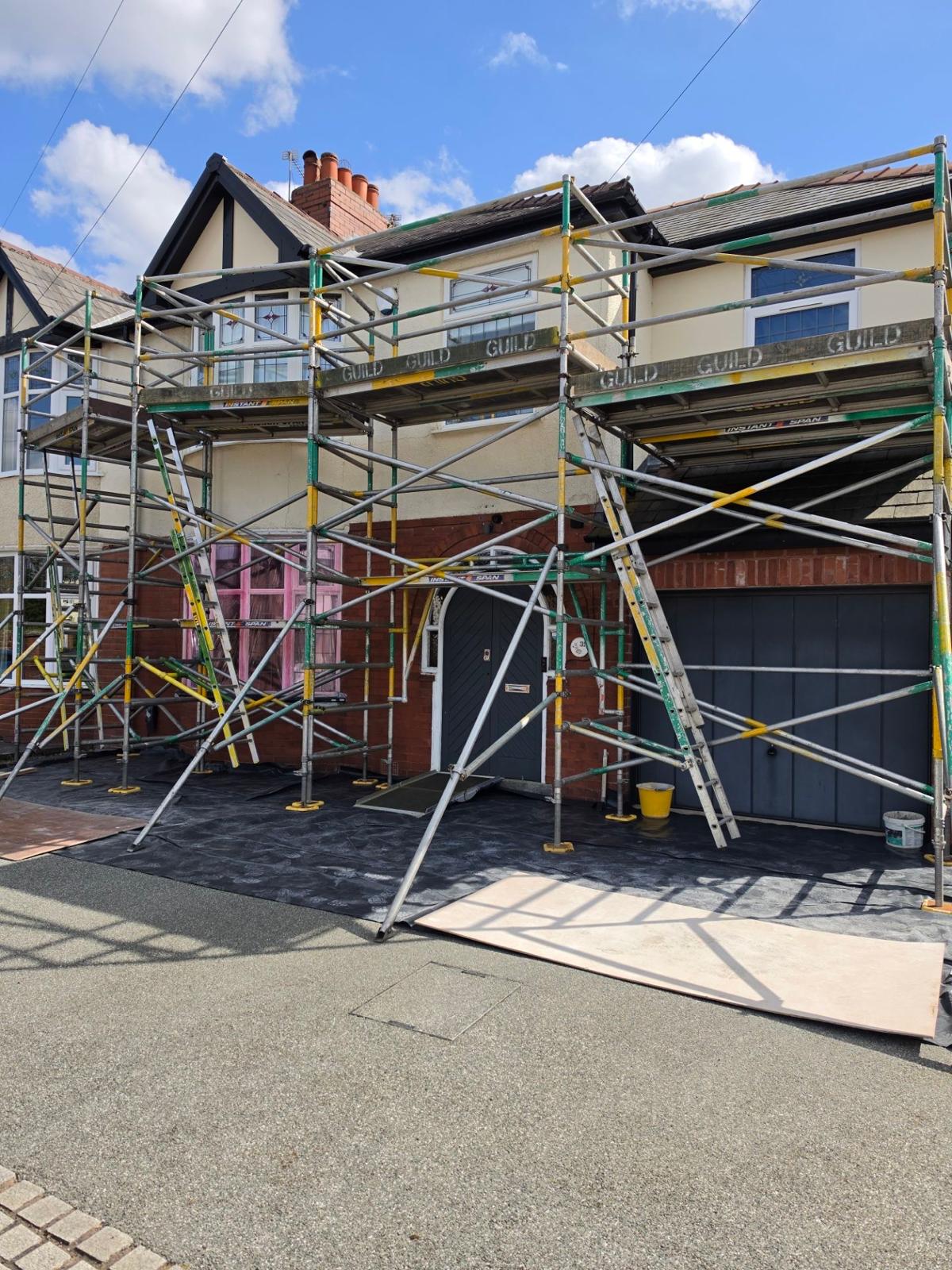 White-painted terraced house, full Guild Scaffolding front wrap on a sunny day