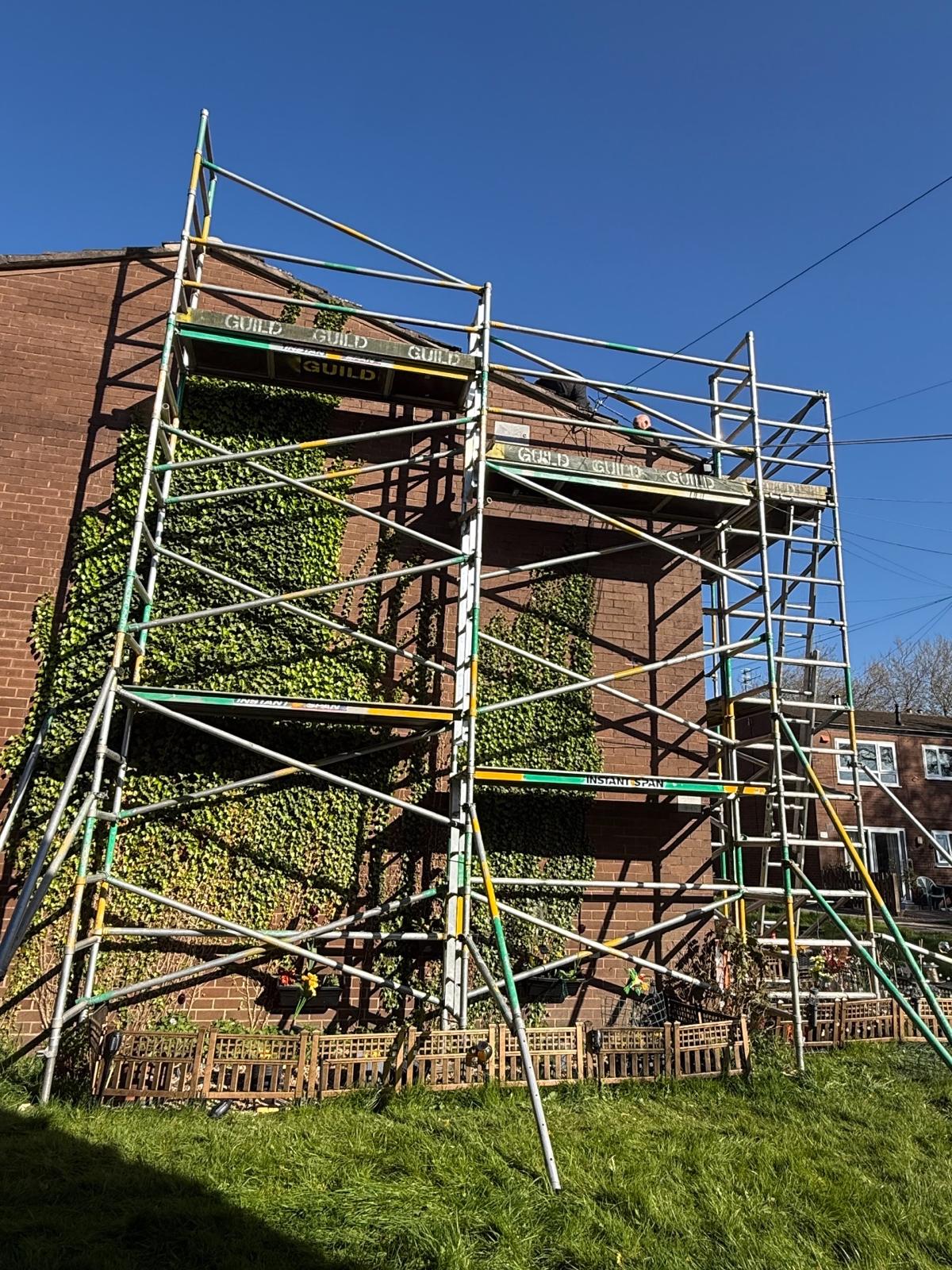 Multi-level brick gable-end access scaffold with crew member on the top platform